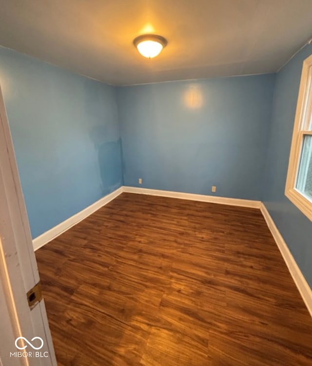 spare room with dark wood finished floors and baseboards