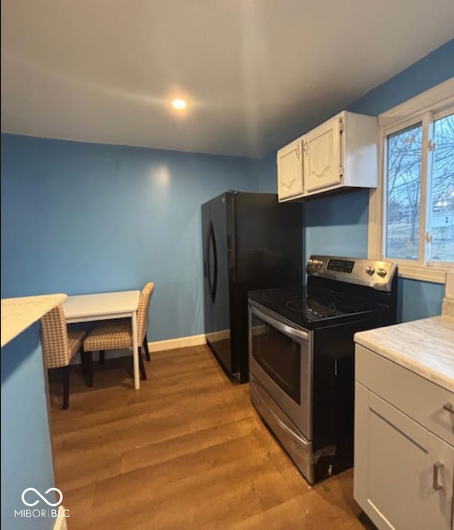 kitchen with baseboards, white cabinets, light countertops, stainless steel electric range oven, and light wood finished floors