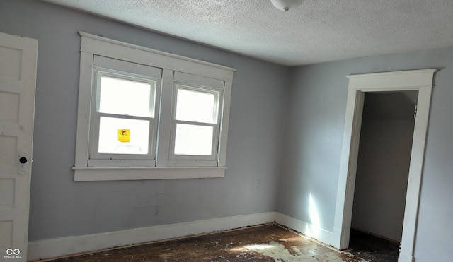 spare room featuring a textured ceiling and baseboards