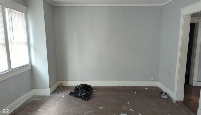 spare room featuring a healthy amount of sunlight, crown molding, and baseboards