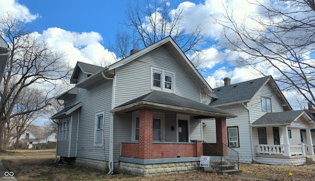 view of front of property featuring covered porch, a shingled roof, and brick siding