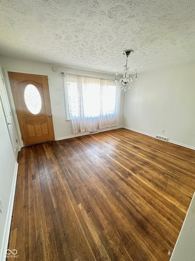 entrance foyer featuring a textured ceiling, wood-type flooring, baseboards, and an inviting chandelier