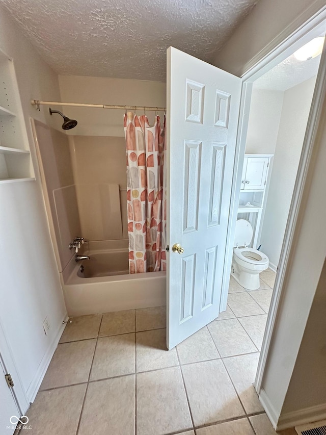 bathroom featuring baseboards, toilet, tile patterned flooring, shower / bath combo with shower curtain, and a textured ceiling