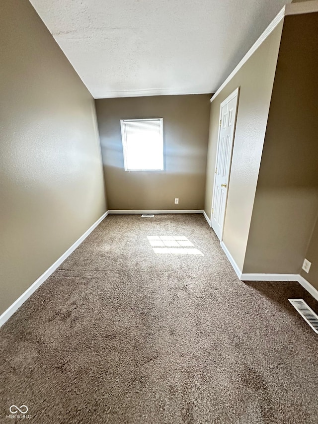 empty room featuring a textured ceiling, carpet floors, visible vents, and baseboards