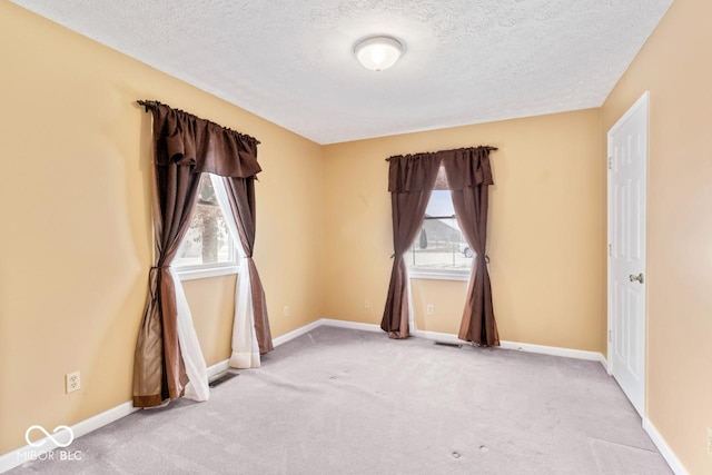 spare room featuring baseboards, carpet floors, and a textured ceiling