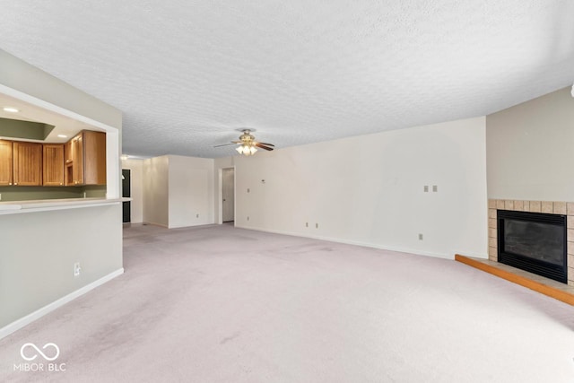 unfurnished living room with light colored carpet, a tile fireplace, a ceiling fan, and baseboards