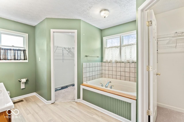 bathroom with a bath, a wealth of natural light, and a textured ceiling