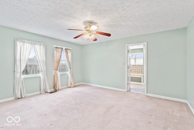 carpeted spare room with a textured ceiling, a ceiling fan, and baseboards