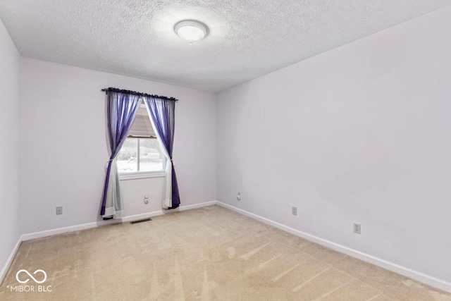 carpeted spare room featuring visible vents, baseboards, and a textured ceiling