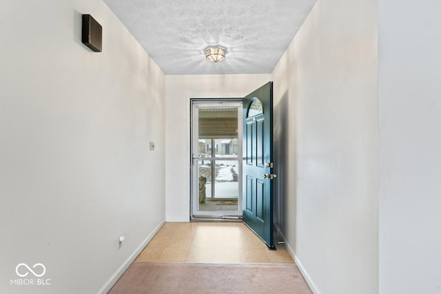 doorway with carpet, baseboards, and a textured ceiling