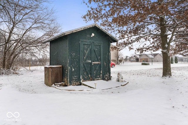 snow covered structure with an outdoor structure and a shed