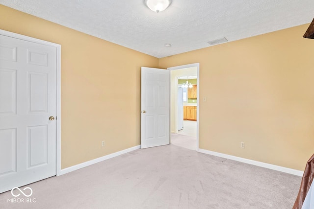 unfurnished bedroom with visible vents, baseboards, light colored carpet, and a textured ceiling