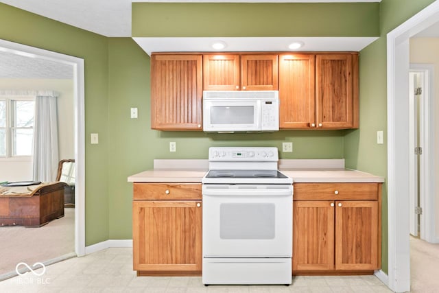 kitchen featuring baseboards, white appliances, light floors, and light countertops