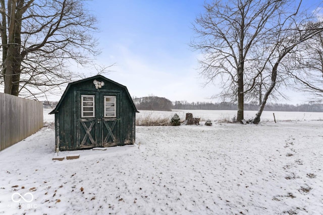 snow covered structure with a storage unit, an outdoor structure, and fence