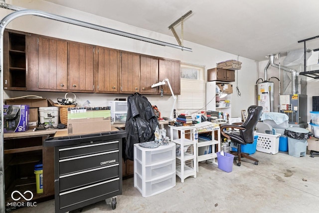 garage featuring heating unit, a workshop area, and water heater