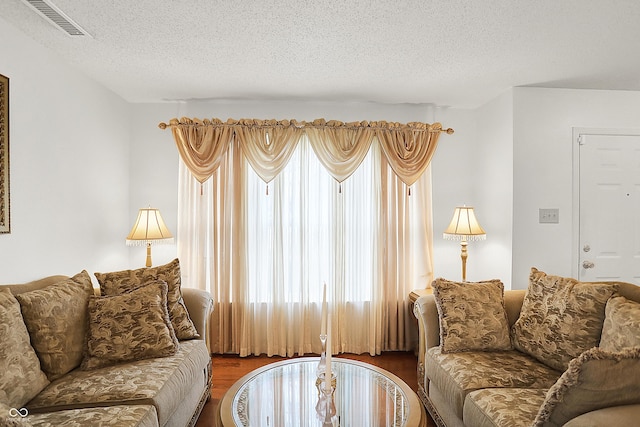 living room with visible vents, a textured ceiling, and wood finished floors