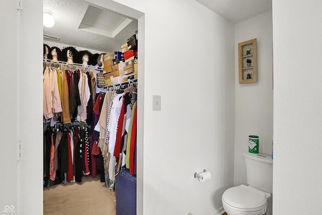 bathroom featuring visible vents, toilet, a textured ceiling, concrete floors, and a spacious closet