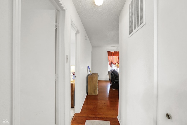 corridor with visible vents, a textured ceiling, and wood finished floors