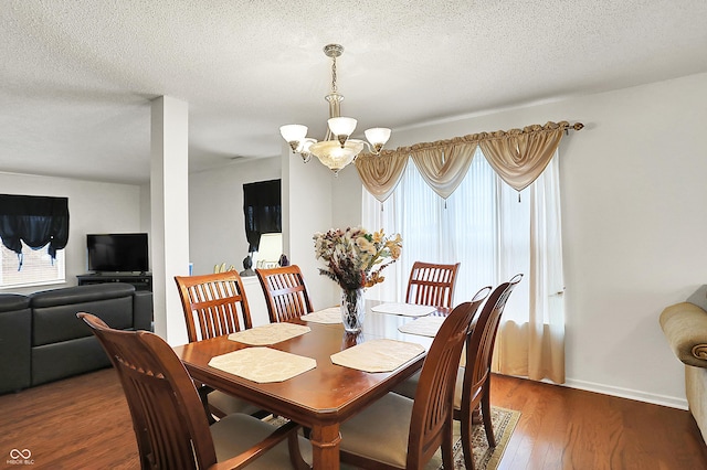 dining area featuring an inviting chandelier, plenty of natural light, wood finished floors, and a textured ceiling