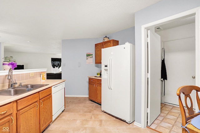 kitchen with visible vents, backsplash, light countertops, white appliances, and a sink