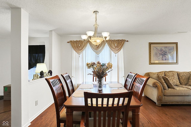 dining room featuring a chandelier, a textured ceiling, visible vents, and wood finished floors