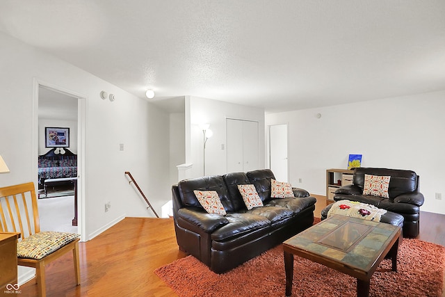 living room featuring light wood-style flooring, baseboards, and a textured ceiling