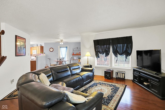 living area featuring baseboards, a textured ceiling, a ceiling fan, and dark wood-style flooring