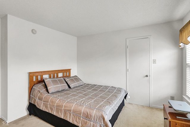 bedroom with light carpet, a textured ceiling, and baseboards