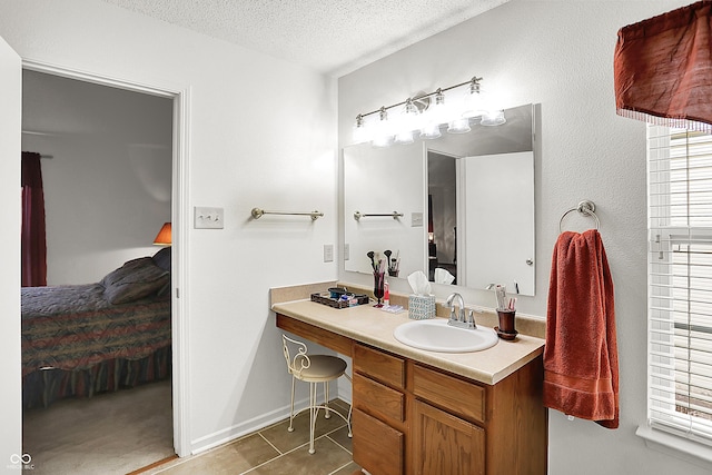 bathroom featuring tile patterned flooring, connected bathroom, baseboards, vanity, and a textured ceiling