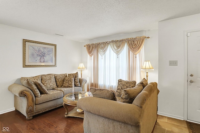 living room featuring dark wood-type flooring, visible vents, baseboards, and a textured ceiling