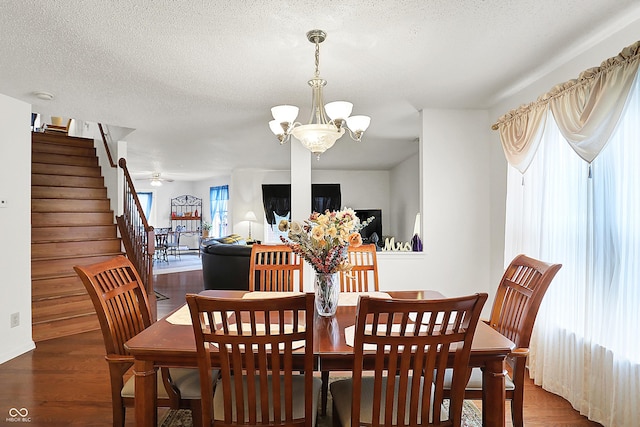 dining room with a textured ceiling, stairway, wood finished floors, and a chandelier