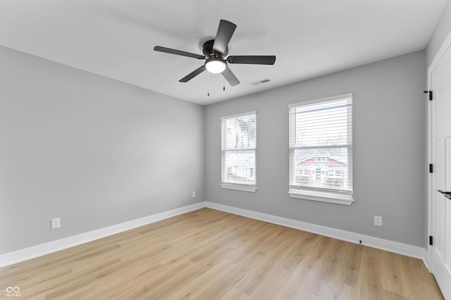 spare room featuring light wood-style floors, baseboards, visible vents, and a ceiling fan