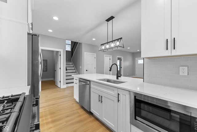 kitchen featuring stainless steel appliances, white cabinetry, a sink, and backsplash