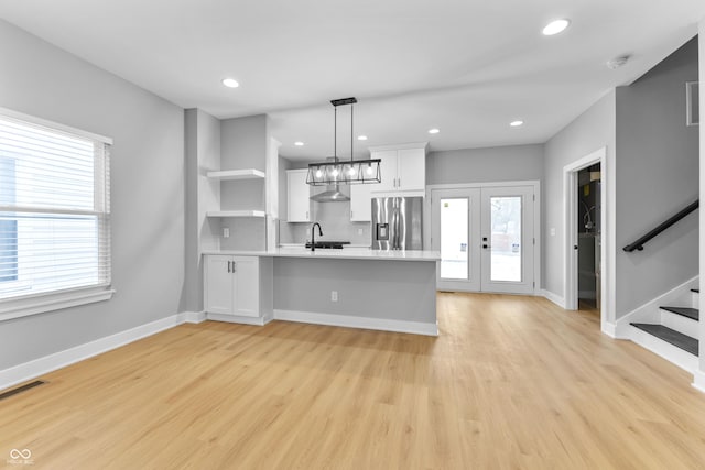 kitchen with stainless steel refrigerator with ice dispenser, visible vents, light countertops, white cabinets, and a peninsula