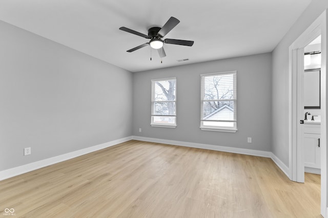 spare room with visible vents, light wood-style floors, a ceiling fan, a sink, and baseboards