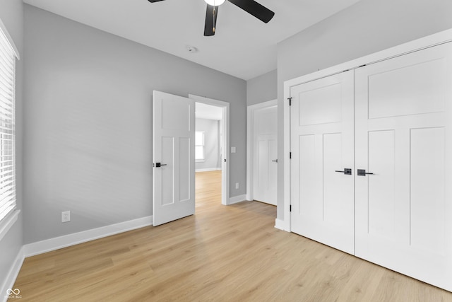 unfurnished bedroom with light wood-style flooring, baseboards, ceiling fan, and a closet