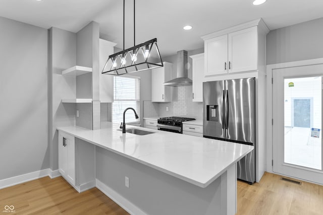 kitchen with open shelves, stainless steel appliances, a sink, a peninsula, and wall chimney exhaust hood