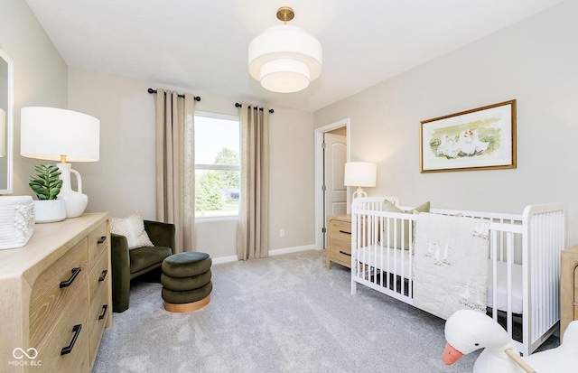 bedroom with a nursery area, light colored carpet, and baseboards