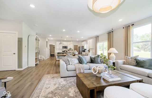 living room featuring baseboards, light wood finished floors, and recessed lighting