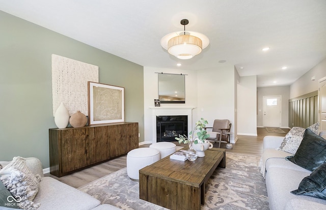 living area with a glass covered fireplace, recessed lighting, baseboards, and wood finished floors