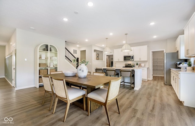 dining space featuring light wood-style floors, recessed lighting, stairway, and baseboards