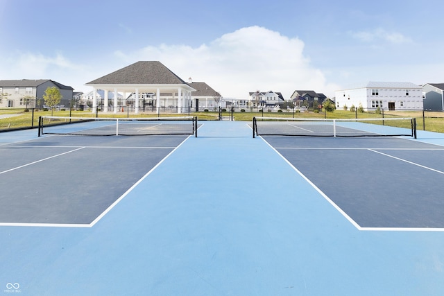 view of tennis court with a residential view and fence