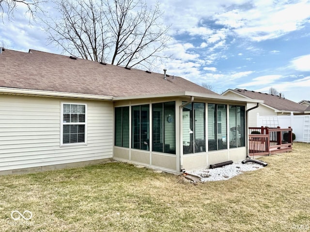 rear view of house featuring a sunroom, fence, a lawn, and roof with shingles