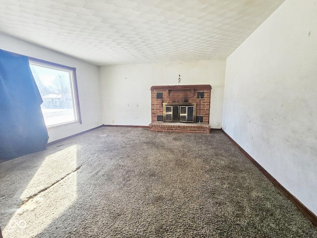 unfurnished living room with carpet floors, a brick fireplace, and baseboards