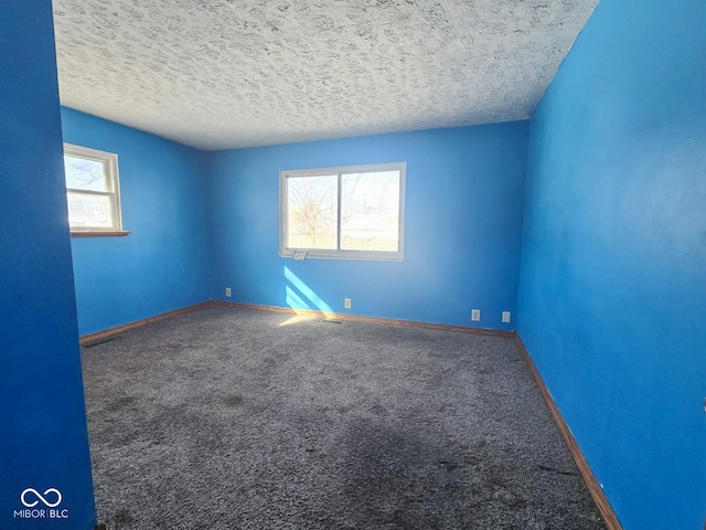 carpeted spare room featuring a textured ceiling and baseboards