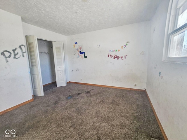 unfurnished bedroom with carpet, a closet, a textured ceiling, and baseboards