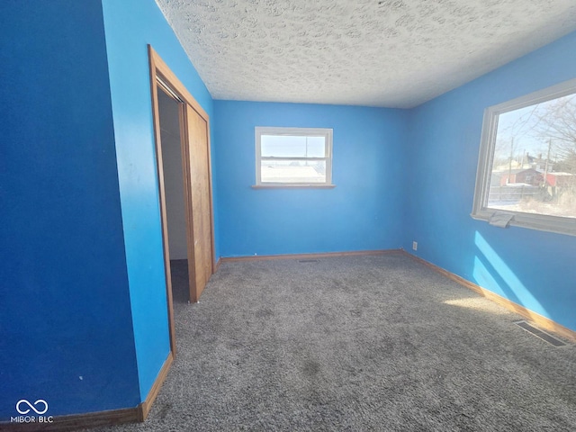 unfurnished bedroom featuring baseboards, visible vents, carpet, a textured ceiling, and a closet