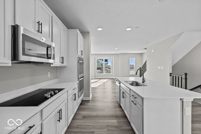 kitchen featuring stainless steel appliances, light countertops, a sink, and wood finished floors