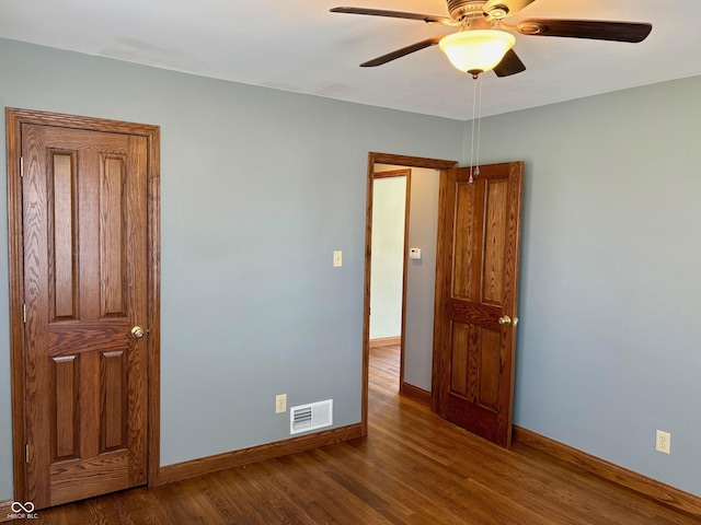 spare room featuring ceiling fan, visible vents, baseboards, and wood finished floors