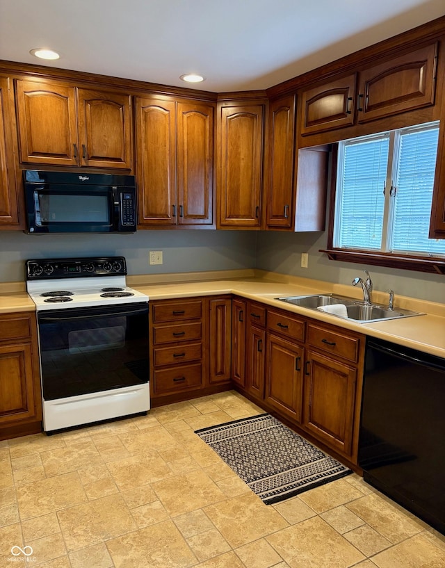 kitchen featuring a sink, black appliances, brown cabinetry, and light countertops